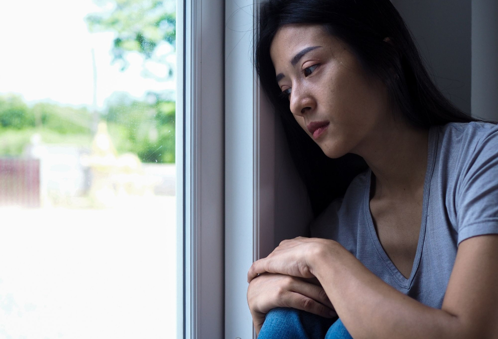 woman looking out of the window looking distressed