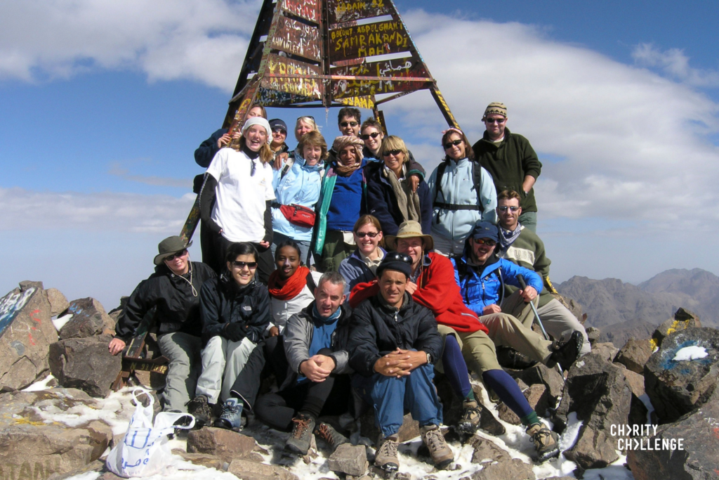 a group of people sitting on top of Mount Toubkal for morocco trek