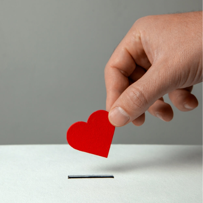 a hand donating a heart inside a box