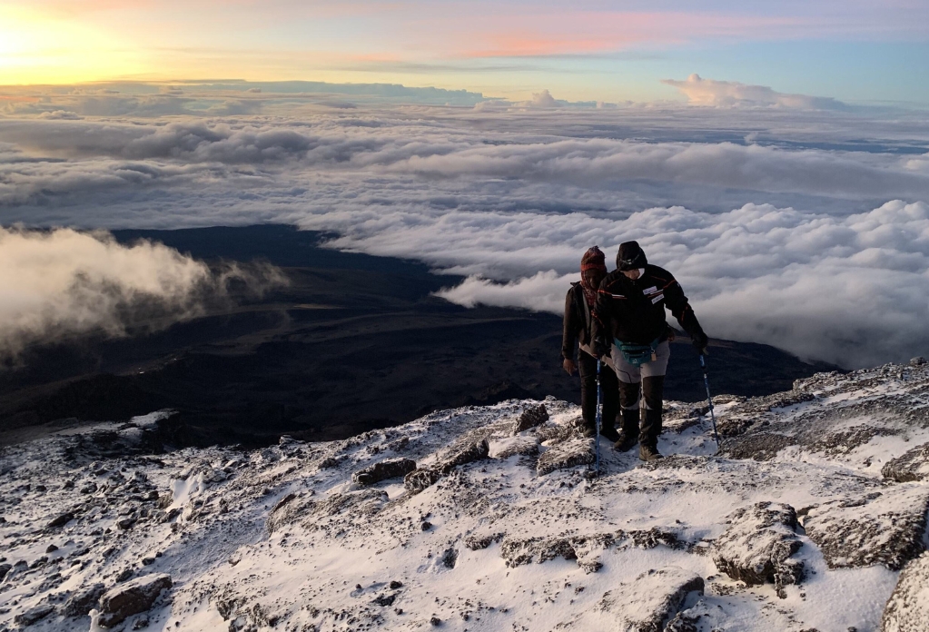 Ian and his guide trek through the snow, above the cloud line on the final approach to the summit of Kilimanjaro