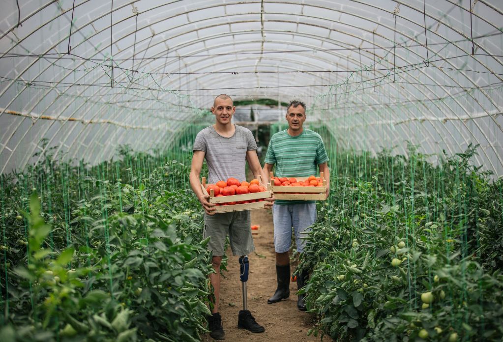 modern slavery in UK agriculture. Image of two seasonal workers holding a basket of fruit.