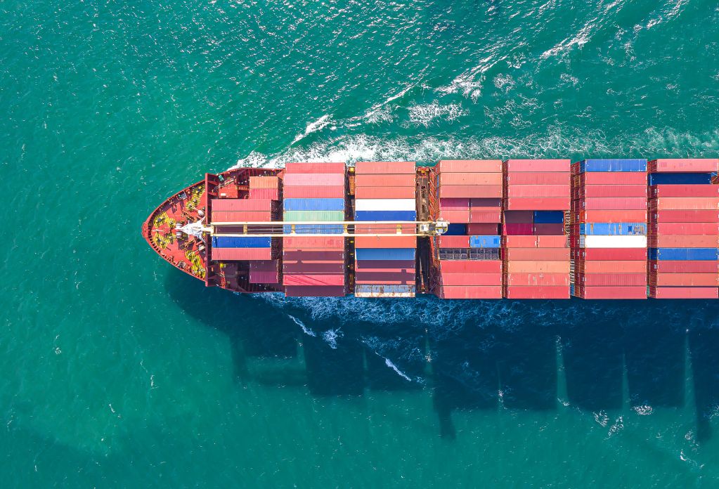 Aerial top view of cargo ship carrying container for import export food to customer, concept logistic and supply chain and transparent communication about modern slavery