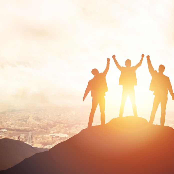 three people standing on top of a cliff overlooking a scenic view of the sunset
